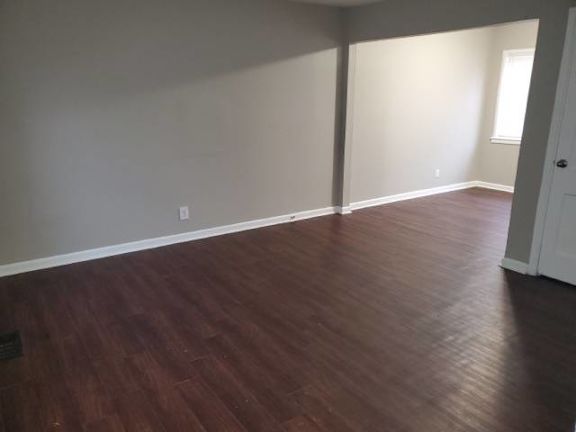 A room with wooden flooring and white walls.