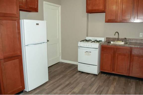A white refrigerator stands in a kitchen with brown cabinets.