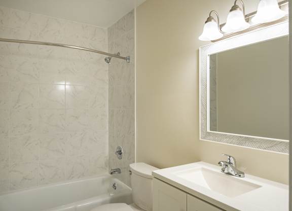 A white bathroom with a tub, sink and mirror.