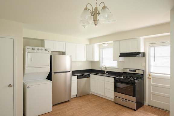 A kitchen with white appliances and wooden floors.
