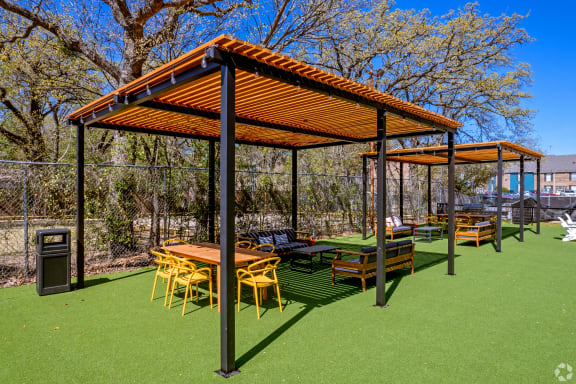 a photo of a picnic area with tables and chairs under a pergola on top of