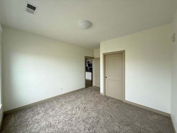 A room with a carpeted floor and a door leading to another room.