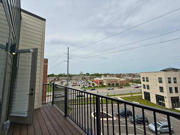A view from a balcony overlooking a parking lot and buildings.