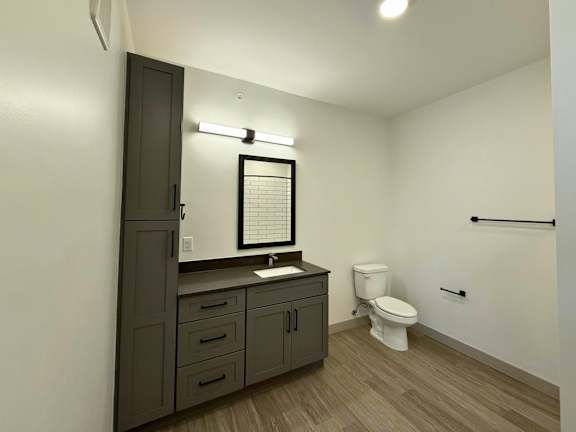 A bathroom with a toilet, sink, and mirror.