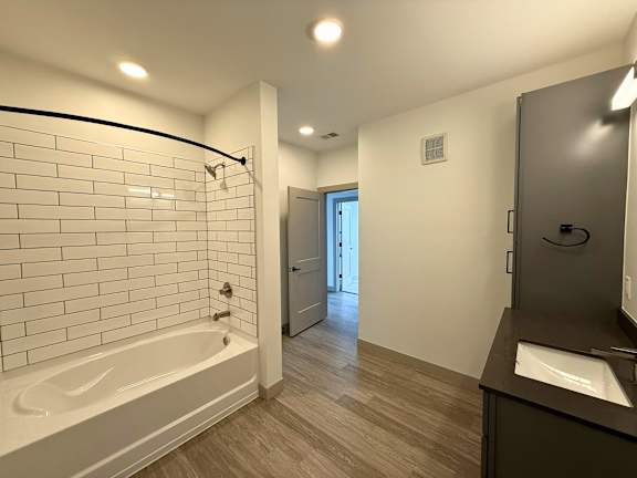 A bathroom with a white tiled shower area and a wooden floor.