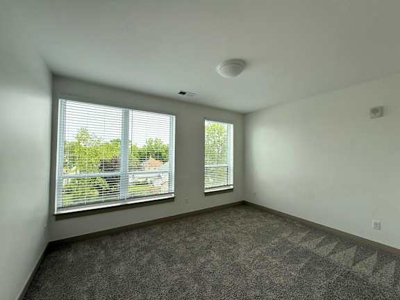 A room with a large window and a carpeted floor.