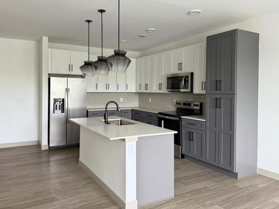 A modern kitchen with a white island and dark wood floors.