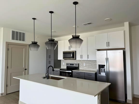 A kitchen with a white counter top and stainless steel appliances.