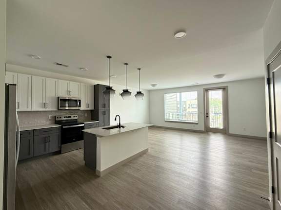 A modern kitchen with a large island and pendant lights.