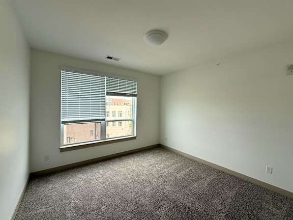 A room with a window and a carpeted floor.
