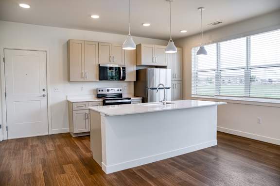 A kitchen with a white island and wooden floors.