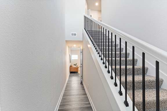 A staircase with a black railing and a grey carpeted runner.