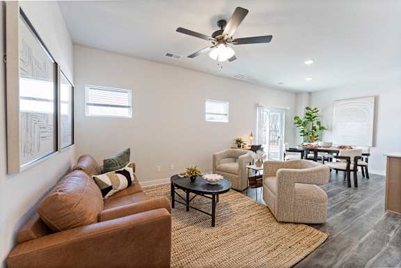 A living room with a brown couch and a ceiling fan.