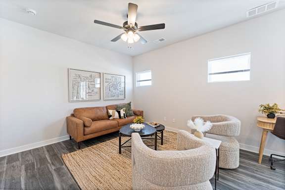 A living room with a brown couch, two chairs, and a coffee table.