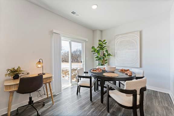 A dining room with a table set for two and a view of the outdoors.