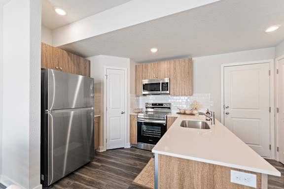 A modern kitchen with a stainless steel refrigerator and a wooden island.
