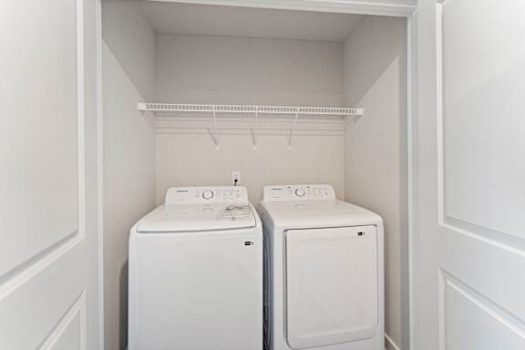 Two white front loading washing machines in a small laundry room.