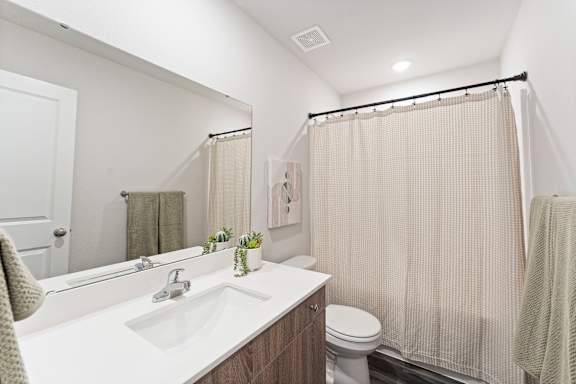 A bathroom with a white countertop and a beige shower curtain.