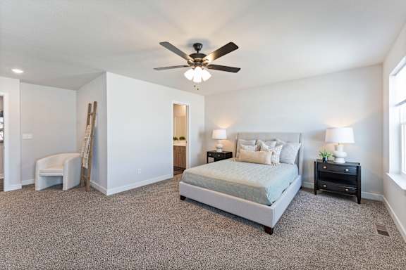 A bedroom with a bed, nightstand, and chair.