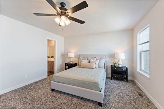 A bedroom with a bed, two nightstands, and a ceiling fan.