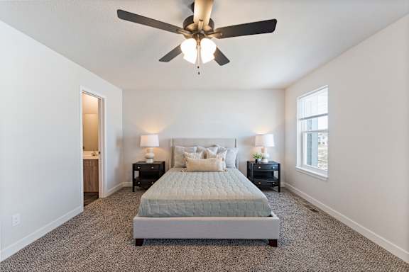 A bedroom with a bed, two nightstands, and a ceiling fan.
