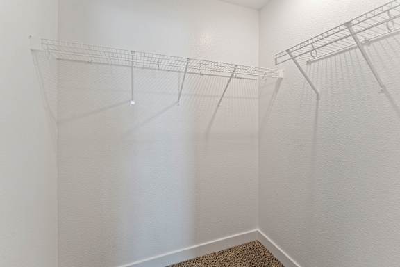 A white closet with a carpeted floor and shelving.