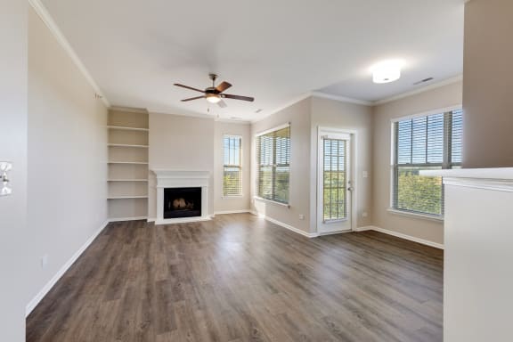 an empty living room with a fireplace and a ceiling fan