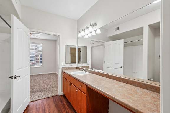 A bathroom with a sink, mirror, and wooden cabinets.