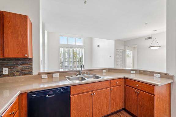 A kitchen with wooden cabinets and a black dishwasher.