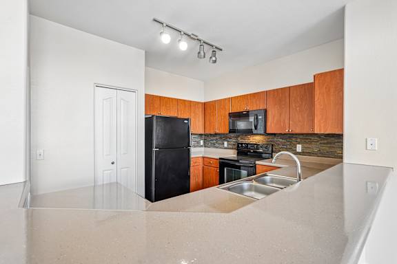 A kitchen with a black fridge, microwave, and stove.