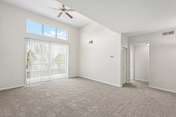A room with a ceiling fan and carpeted floor.