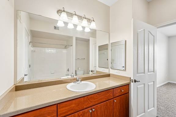 A bathroom with a sink, mirror, and lighting fixture.