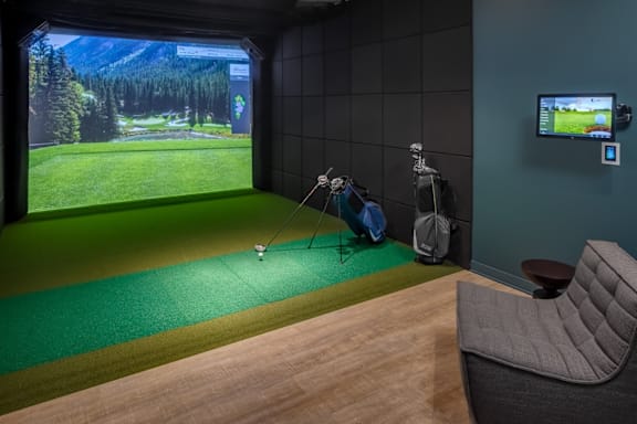 A room with a golf simulator and a chair.
