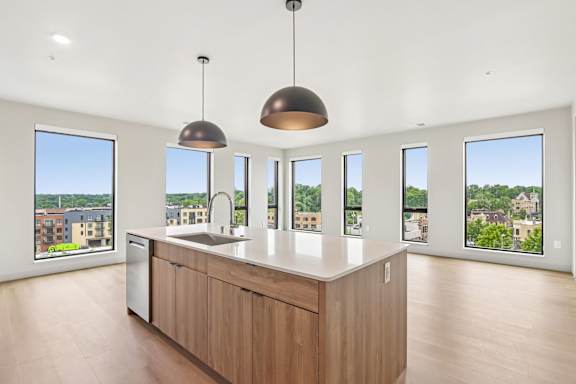 A kitchen with a large island and pendant lights.