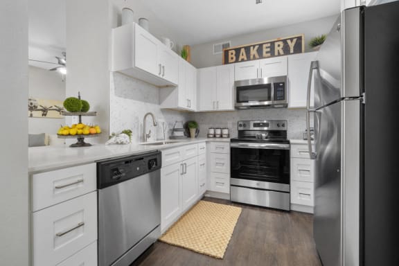 Kitchen with stainless steel appliances, white cabinets, hardwood style flooring and granite countertops