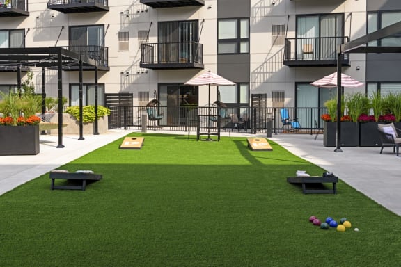 a grassy area with benches and umbrellas in front of an apartment building