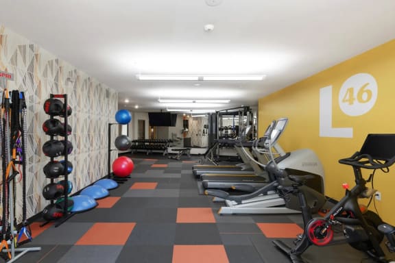 a gym with cardio equipment and weights on the wall