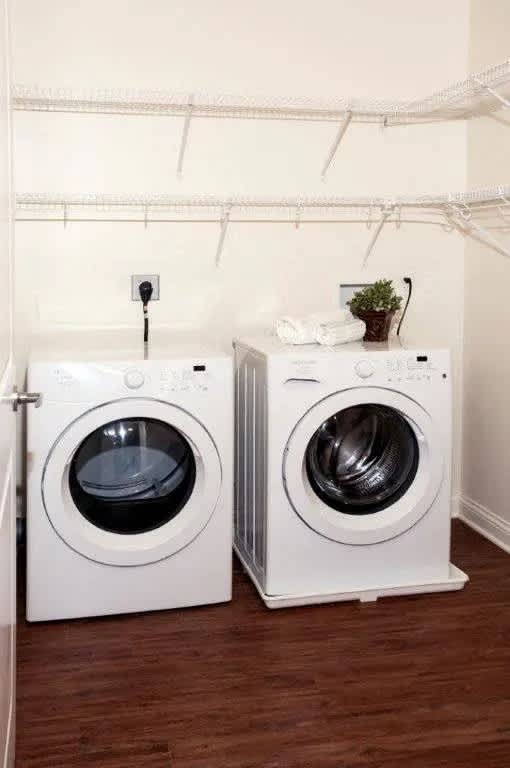 Two white front loading washing machines in a laundry room.