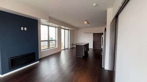 A spacious living room with a fireplace and a kitchen area in the background.