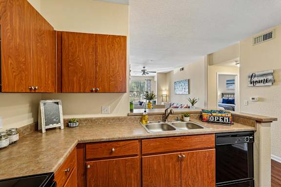 A kitchen with wooden cabinets and a countertop with a sign that says "Open".