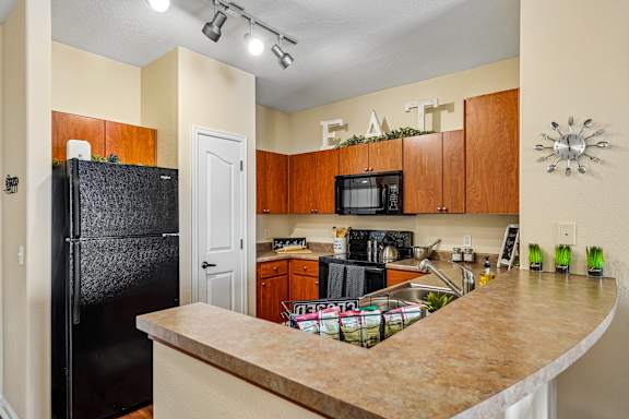 A kitchen with a black fridge and wooden cabinets.