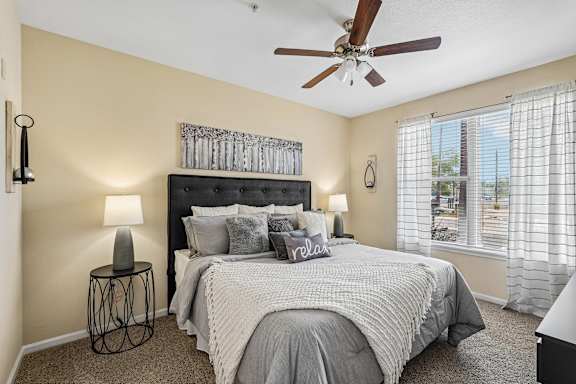 A bedroom with a large bed and a ceiling fan.