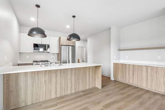 A modern kitchen with a wooden counter and pendant lights.