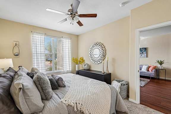 A bedroom with a bed, a dresser, a mirror, and a ceiling fan.