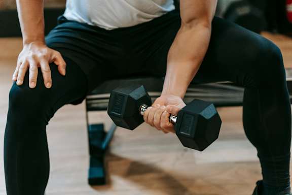 A man is lifting a dumbbell in a gym.