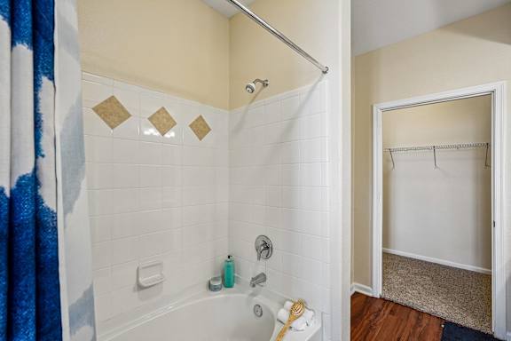 A bathroom with a white tub and a blue shower curtain.