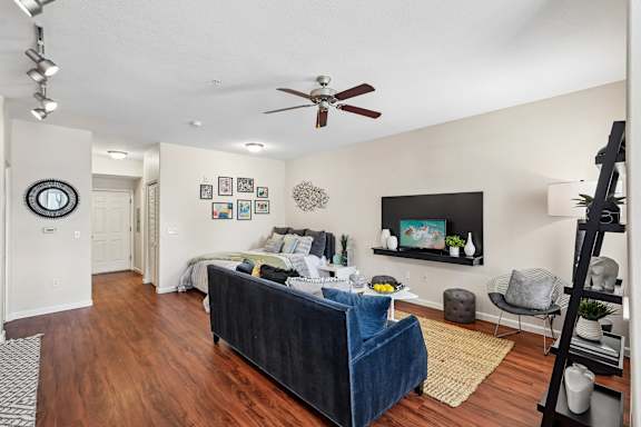 A living room with a blue couch and a ceiling fan.