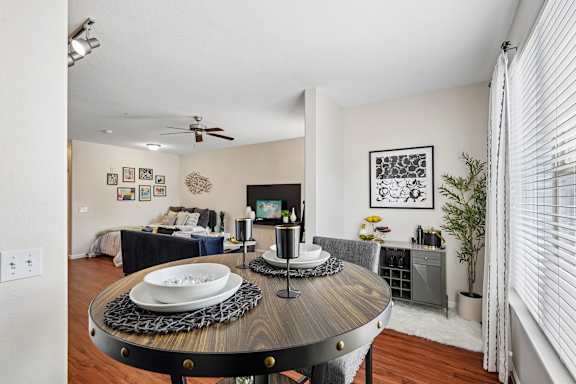 A dining room with a table set for two and a television in the corner.