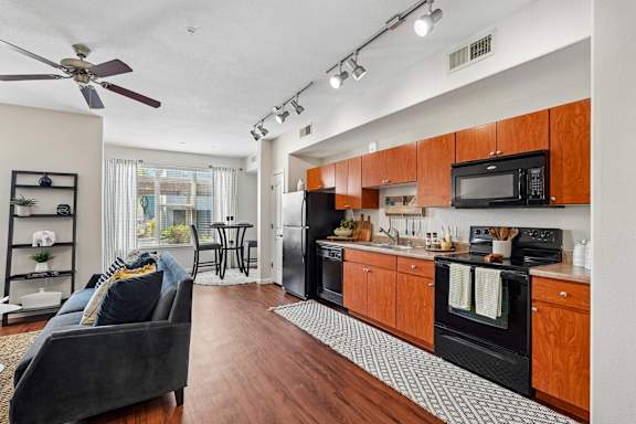 A modern kitchen with wooden cabinets and black appliances.