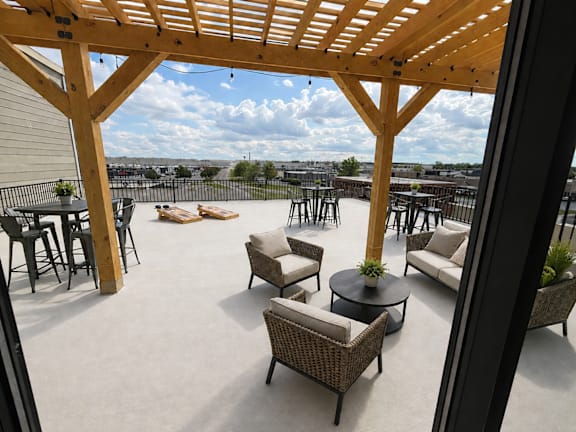 A patio with a wooden pergola and wicker furniture.